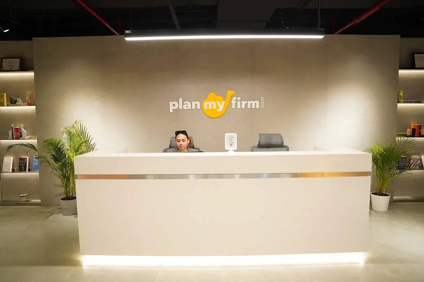 PlanMyFirm reception desk with the brand logo behind it