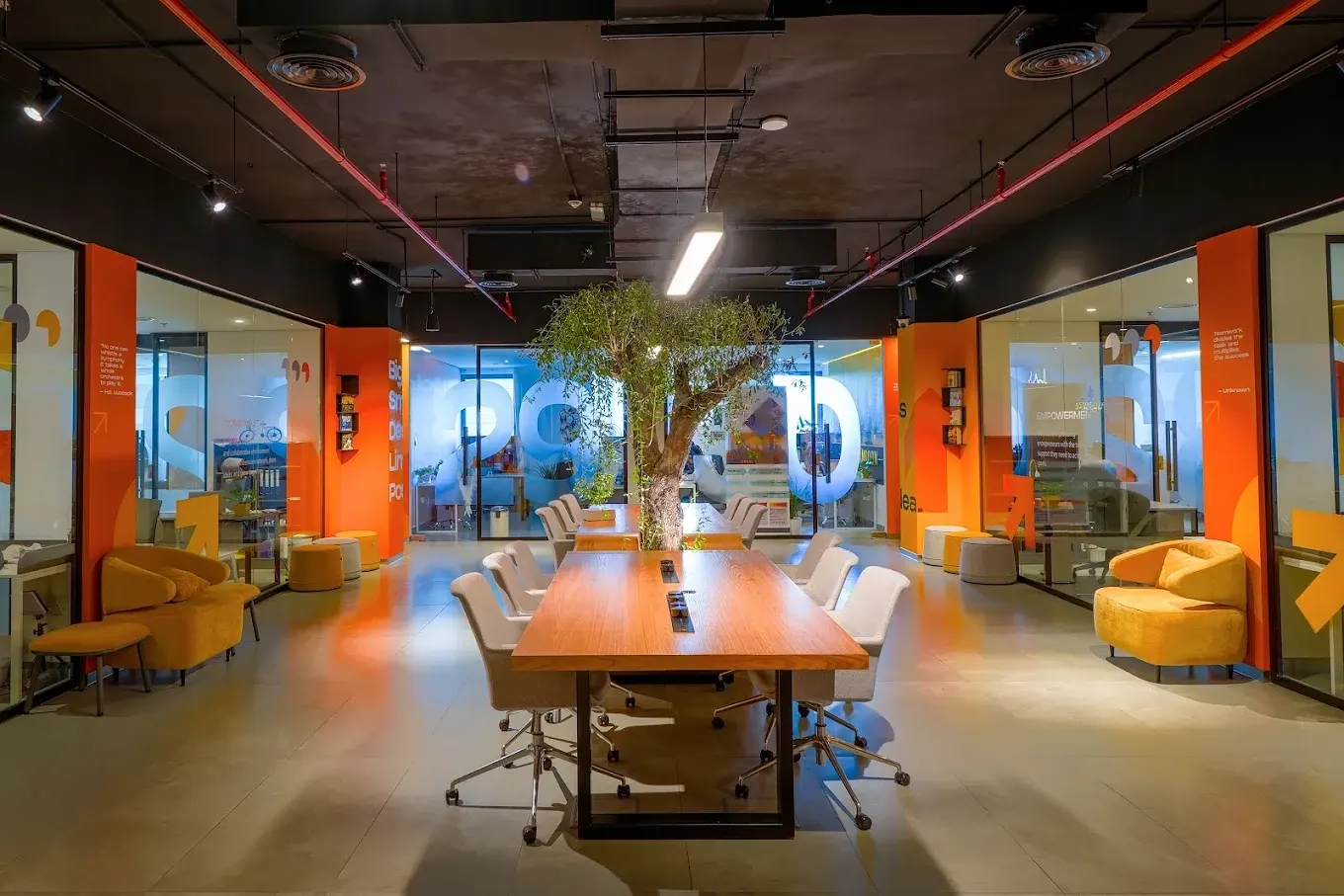 Co-working hall in warm evening light with private offices around it