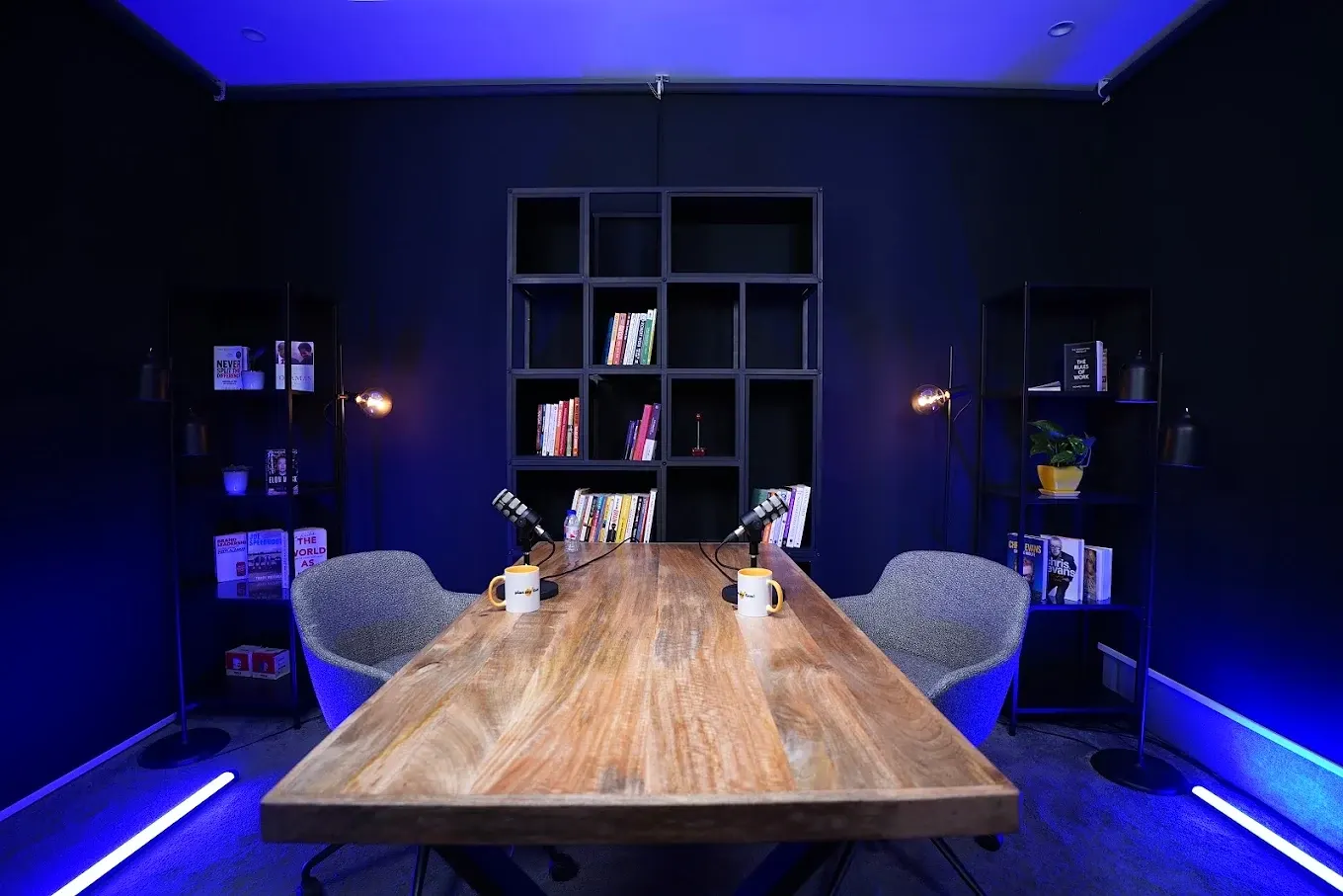 Podcast room with two microphones, bookshelves and blue accent lighting