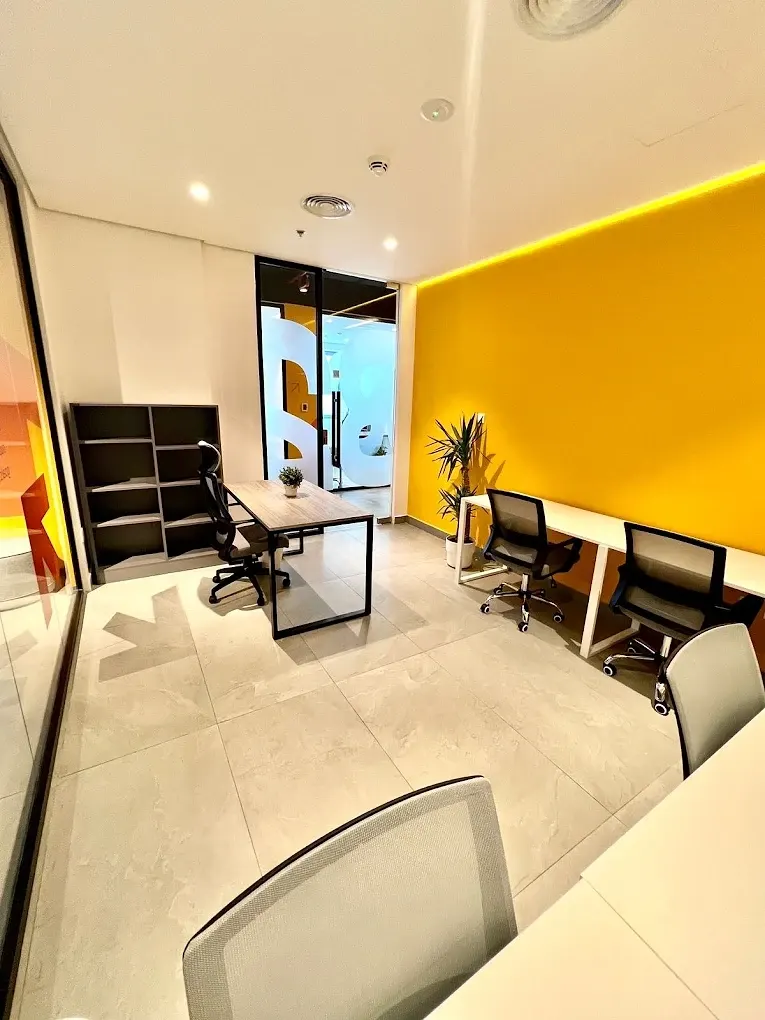 Private office with a yellow feature wall and four desks